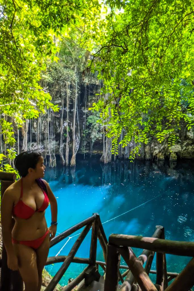 A woman looks out at the blue waters of a cenote in the Yucatan peninsula in Mexico.